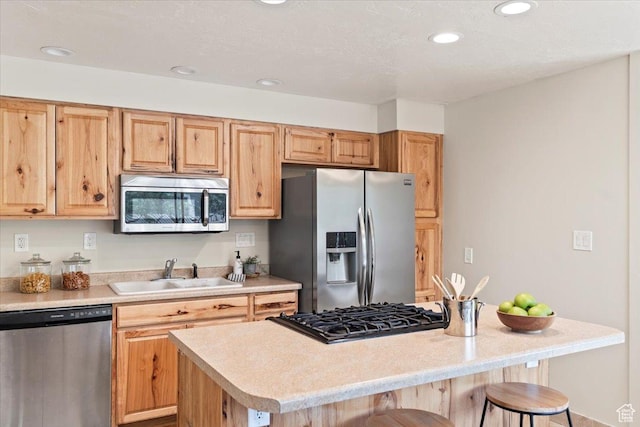 kitchen with a sink, stainless steel appliances, a kitchen bar, and light countertops