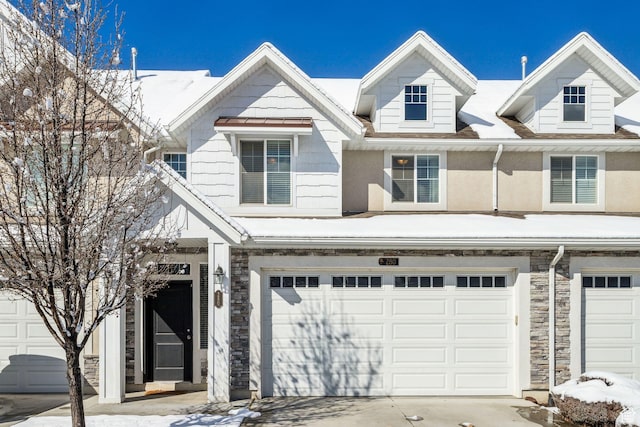 multi unit property featuring an attached garage, driveway, and stone siding
