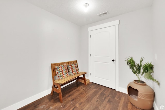 sitting room featuring visible vents, dark wood-type flooring, and baseboards