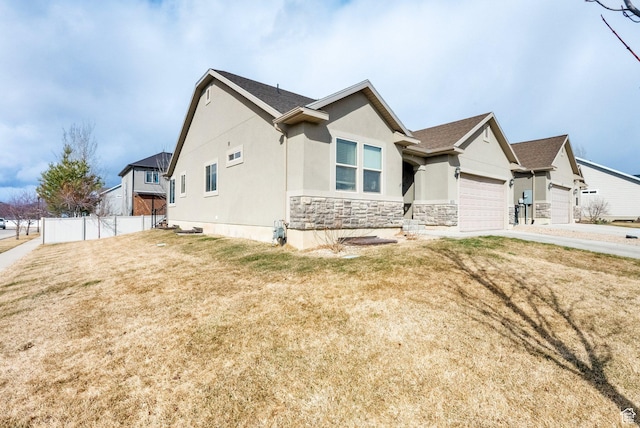 view of front of home with a front yard, fence, stucco siding, a garage, and stone siding