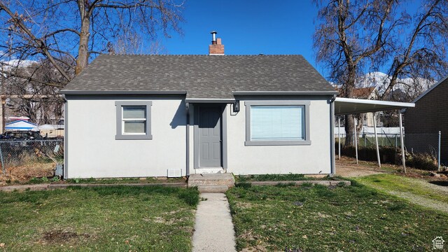 bungalow with a front lawn, fence, a carport, and a chimney