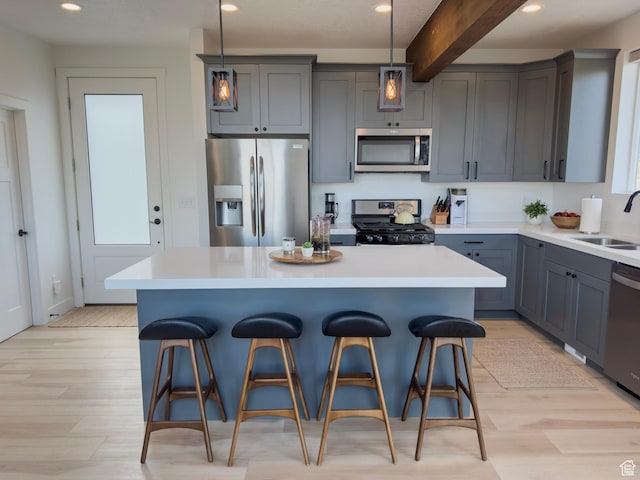 203 Valleyview, Coalville, UT 84017 - kitchen featuring appliances with stainless steel finishes, light wood-style floors, a kitchen bar, beam ceiling, and a kitchen island