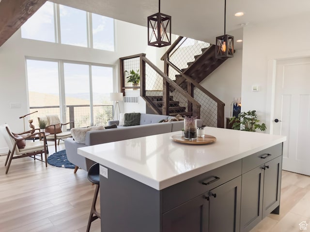 kitchen with a kitchen island, light wood-style flooring, gray cabinets, light countertops, and decorative light fixtures