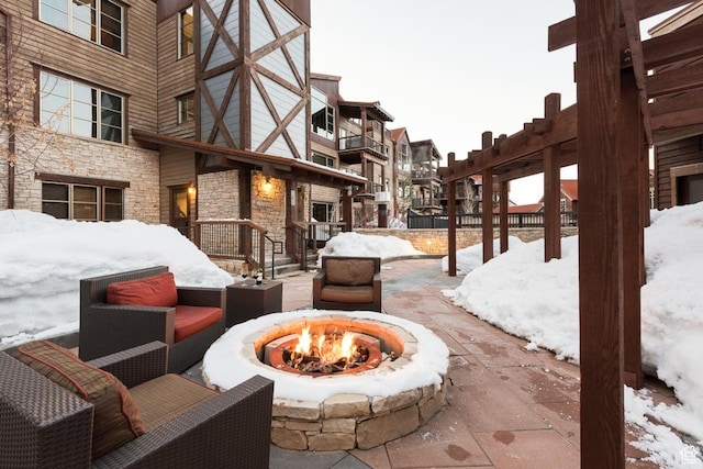 snow covered patio featuring an outdoor fire pit