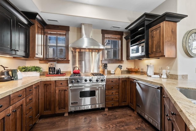 kitchen featuring light stone countertops, visible vents, dark wood-type flooring, appliances with stainless steel finishes, and wall chimney range hood