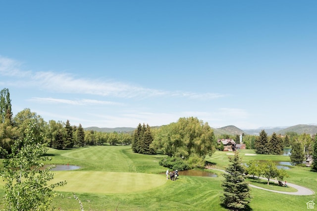 view of home's community with view of golf course, a yard, and a water and mountain view