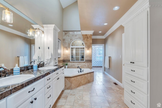 full bath with a garden tub, stone tile floors, ornamental molding, and a sink