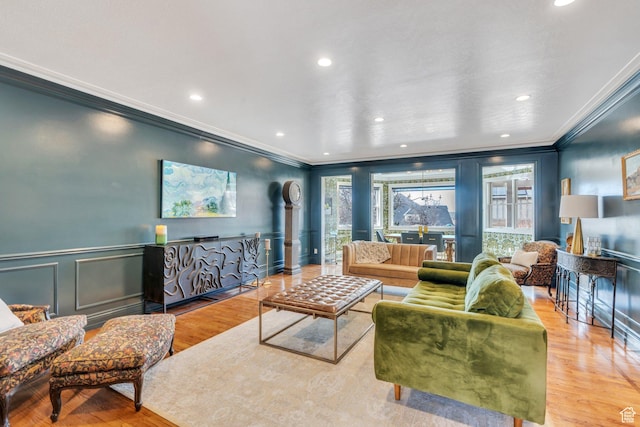 living room featuring crown molding, a wainscoted wall, recessed lighting, wood finished floors, and a decorative wall