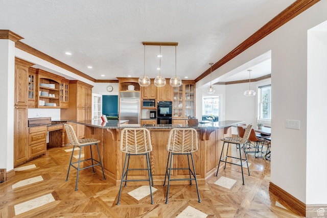 kitchen featuring a kitchen breakfast bar, built in appliances, brown cabinets, and built in study area
