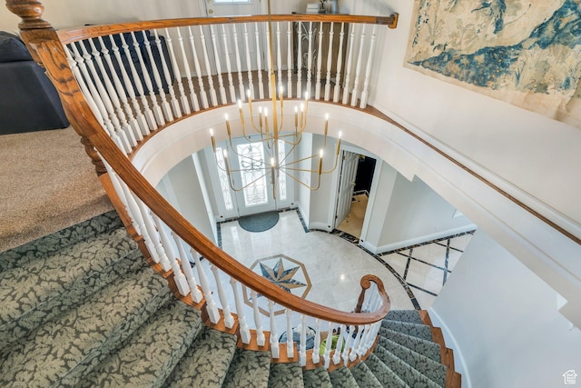 stairway with arched walkways and an inviting chandelier