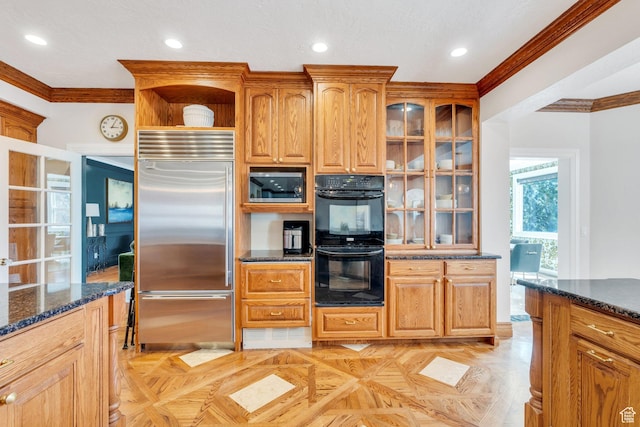 kitchen featuring dark stone countertops, glass insert cabinets, built in appliances, and crown molding