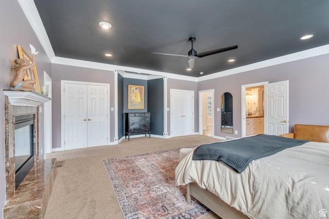 carpeted bedroom with baseboards, multiple closets, a tiled fireplace, ornamental molding, and recessed lighting
