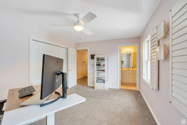 carpeted home office featuring baseboards and ceiling fan