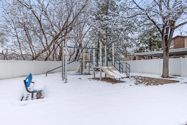yard covered in snow with a playground and a fenced backyard