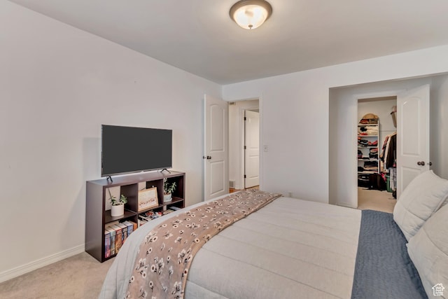 carpeted bedroom with a walk in closet and baseboards