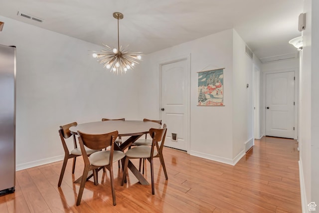 dining room with a chandelier, visible vents, and light wood-style flooring