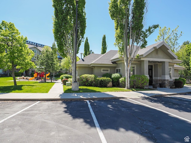 1230 E Privet Dr Unit 214, Salt Lake City, UT 84121 - view of front of house with stucco siding, uncovered parking, a front yard, and stone siding