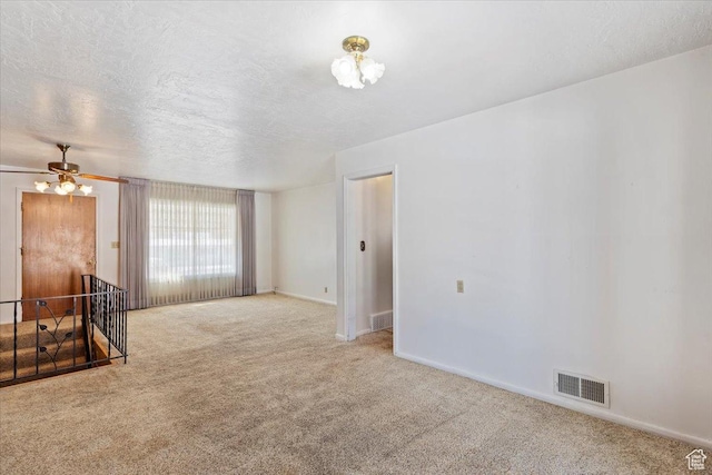 empty room with baseboards, carpet flooring, a textured ceiling, and visible vents