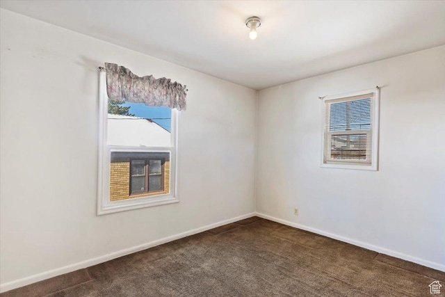 unfurnished room with baseboards, plenty of natural light, and dark carpet