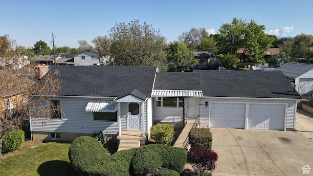 view of front of home featuring an attached garage, a shingled roof, a chimney, and concrete driveway