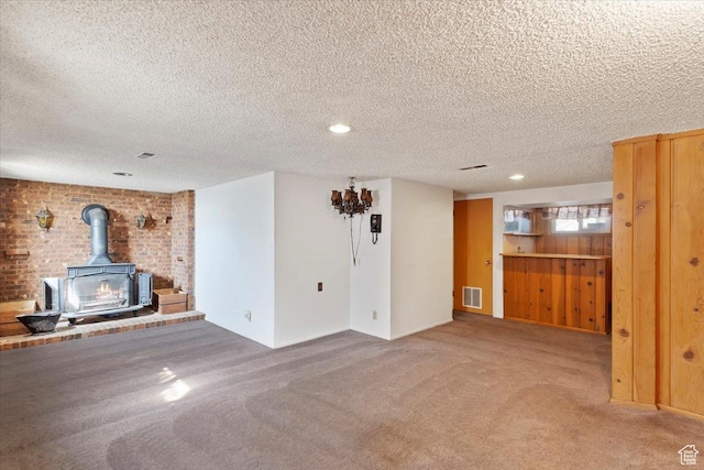 unfurnished living room featuring a wood stove, a textured ceiling, visible vents, and carpet