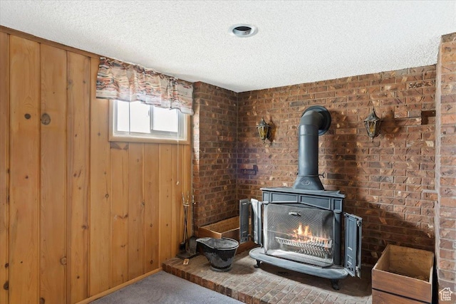 interior details featuring carpet floors, a wood stove, a textured ceiling, and wood walls