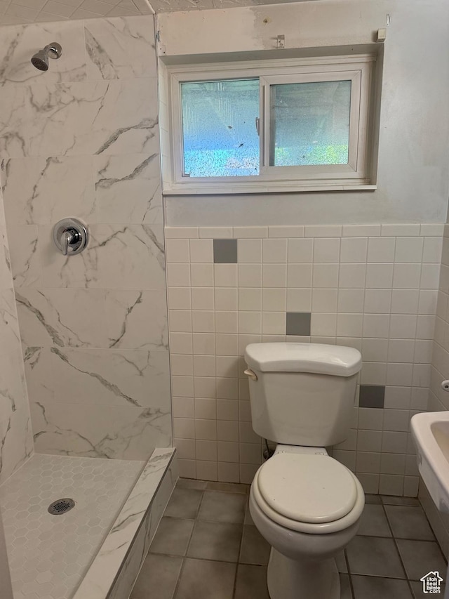 full bathroom with tile walls, a walk in shower, a wainscoted wall, tile patterned floors, and toilet