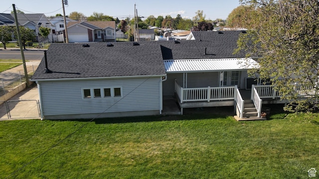 rear view of house featuring a residential view, a shingled roof, and a yard
