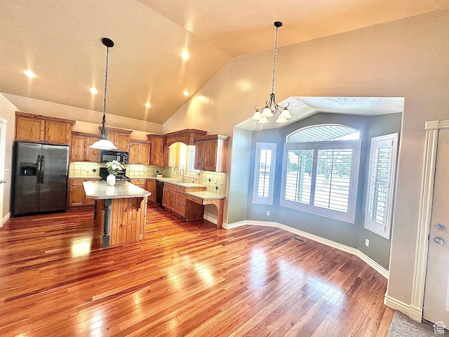 3427 N 2500 W, Farr West, UT 84404 - kitchen featuring a notable chandelier, black appliances, tasteful backsplash, brown cabinetry, and light countertops