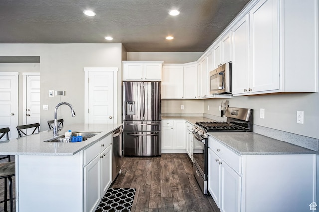 5731 W Osprey Dr, Stansbury Park, UT 84074 - kitchen featuring appliances with stainless steel finishes, a sink, a kitchen breakfast bar, dark wood-type flooring, and white cabinetry