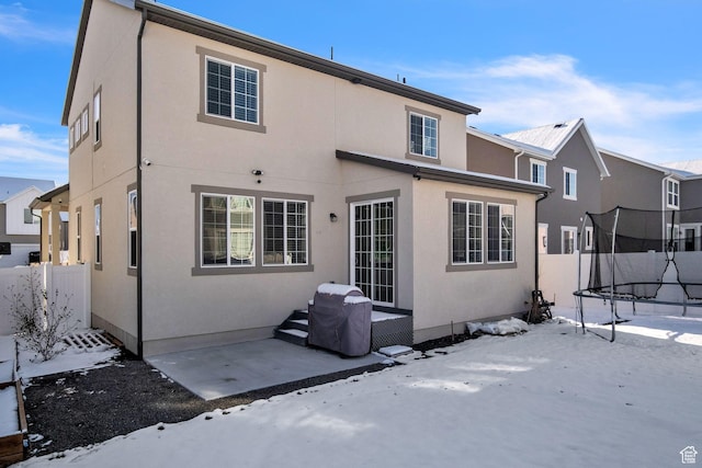 5731 W Osprey Dr, Stansbury Park, UT 84074 - snow covered property featuring a trampoline, a patio area, and stucco siding