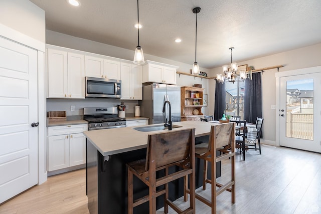 973 N Ledger Dr, Saratoga Springs, UT 84045 - kitchen featuring a kitchen island with sink, stainless steel appliances, light wood-type flooring, and a sink