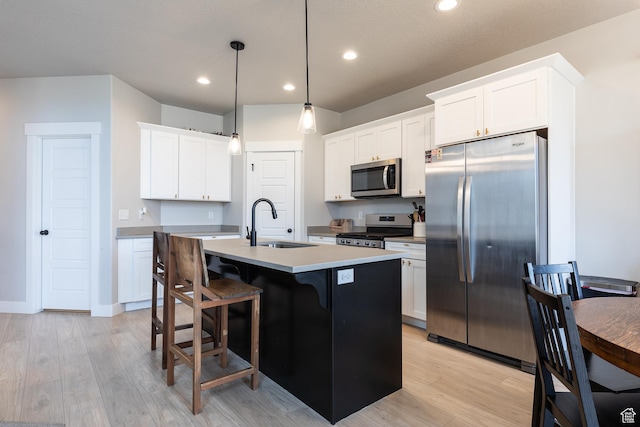 973 N Ledger Dr, Saratoga Springs, UT 84045 - kitchen featuring a kitchen island with sink, a sink, white cabinetry, appliances with stainless steel finishes, and light wood finished floors