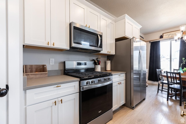 973 N Ledger Dr, Saratoga Springs, UT 84045 - kitchen featuring light wood-type flooring, stainless steel appliances, a textured ceiling, and white cabinetry