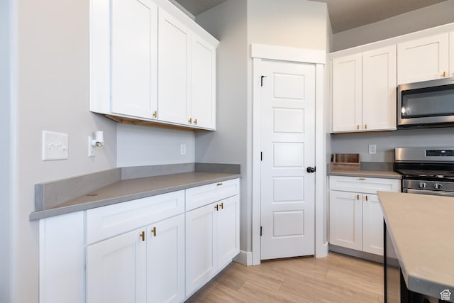 973 N Ledger Dr, Saratoga Springs, UT 84045 - kitchen with light wood-style flooring, appliances with stainless steel finishes, white cabinets, and light countertops