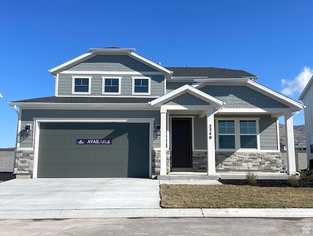 view of front of property featuring an attached garage, concrete driveway, and stone siding