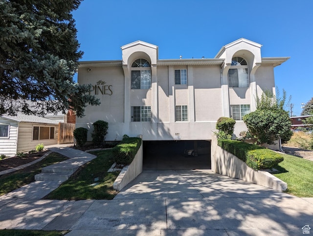 view of front facade with stucco siding, an attached garage, and concrete driveway