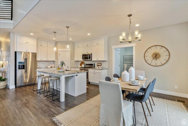 4089 W 1700 N Unit 618, Lehi, UT 84043 - kitchen featuring dark wood-style flooring, decorative backsplash, white cabinets, appliances with stainless steel finishes, and a chandelier
