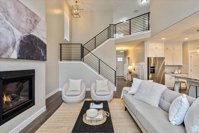 4089 W 1700 N Unit 618, Lehi, UT 84043 - living room with stairway, baseboards, dark wood-type flooring, a towering ceiling, and a glass covered fireplace