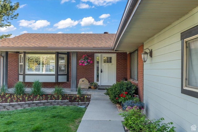 1411 E Elm Leaf Cv, Salt Lake City, UT 84117 - view of exterior entry featuring brick siding, covered porch, and roof with shingles