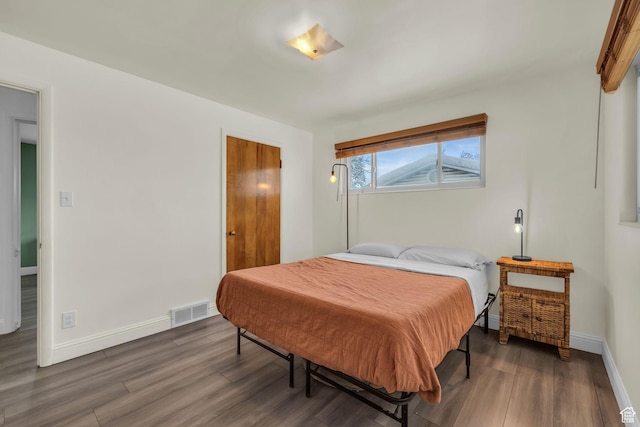 bedroom with visible vents, baseboards, and wood finished floors