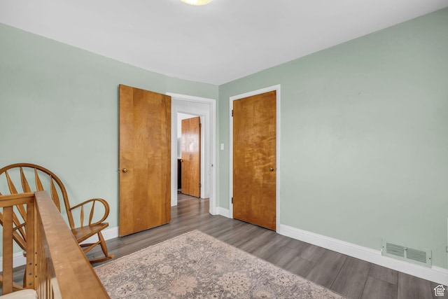 unfurnished bedroom featuring visible vents, baseboards, and wood finished floors