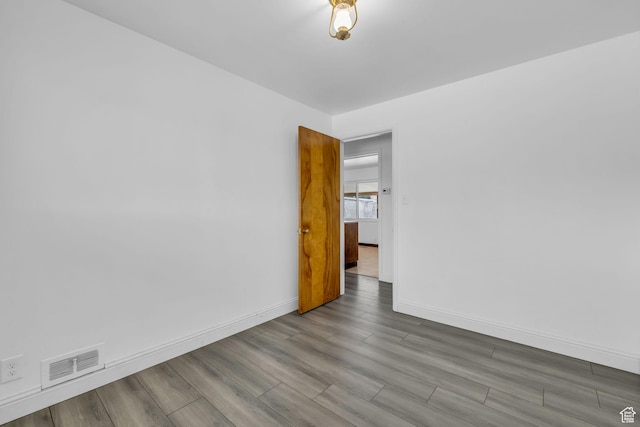 spare room with visible vents, baseboards, and wood finished floors