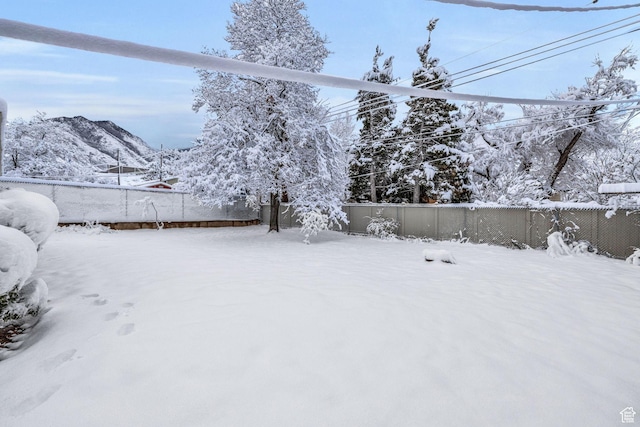 yard layered in snow featuring a fenced backyard and a mountain view