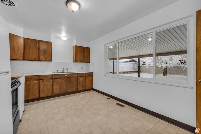 kitchen featuring visible vents, light countertops, baseboards, and a sink