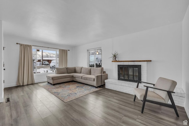 living area featuring a brick fireplace and wood finished floors