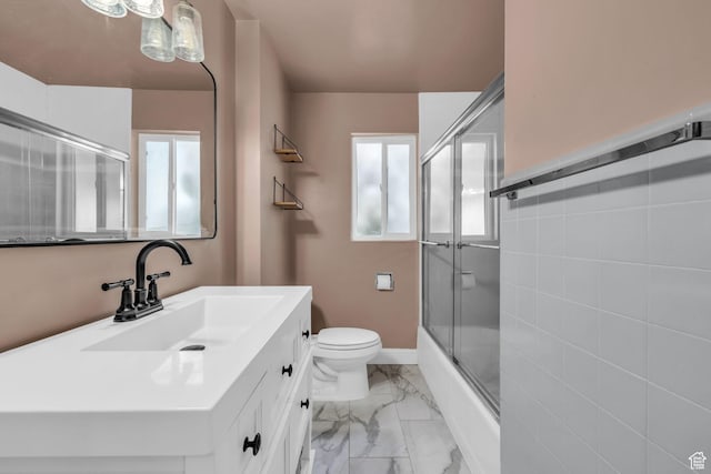 full bathroom featuring toilet, marble finish floor, vanity, and a healthy amount of sunlight