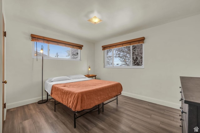 bedroom featuring baseboards, multiple windows, and dark wood finished floors