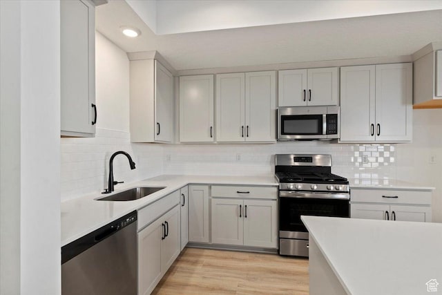kitchen featuring stainless steel appliances, a sink, light countertops, recessed lighting, and tasteful backsplash