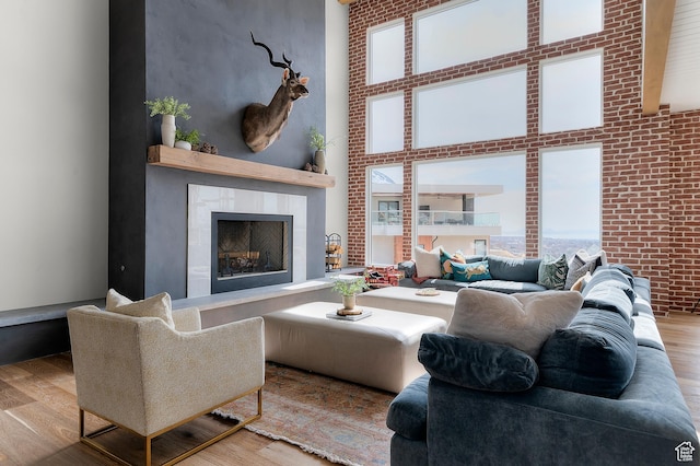 3878 W Oak Hill Dr, Alpine, UT 84004 - living room featuring a fireplace, brick wall, wood finished floors, and a towering ceiling